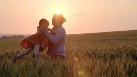 junge-asiatische-Familie-in-einem-Feld-mit-einem-Baby-1-Jahr-auf-der-Hand,-das-Konzept-von-Familienglück,-schöne-Sonne,-Sonnenuntergang,-Slow-motion