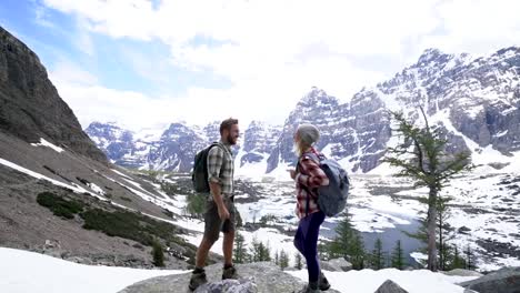 Junges-Paar-in-den-kanadischen-Rockies-Wandern-erreichen-Berggipfel-und-feiern-mit-einer-Umarmung