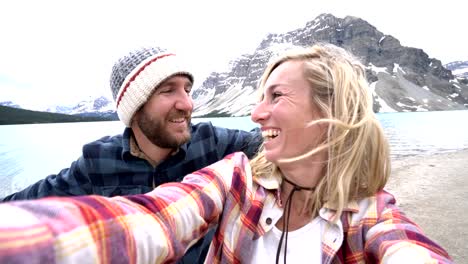 Couple-travelling-in-Canada-taking-selfies-by-stunning-mountain-lake-scenery