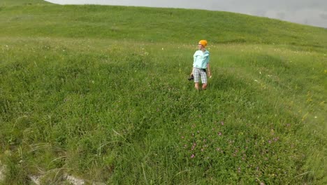 The-girl-photographer-in-glasses-and-a-hat-walks-with-her-dslr-camera-on-the-edge-of-the-plateau-near-the-precipice.-Aerial-view