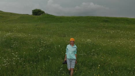 El-fotógrafo-de-la-chica-de-gafas-y-un-sombrero-camina-con-su-cámara-réflex-digital-en-el-borde-de-la-meseta-cerca-del-precipicio.-Vista-aérea