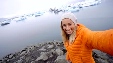 4K-Young-woman-taking-selfie-with-glacier-lake,-icebergs-floating-on-water