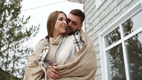 Pareja-abrazándose-en-el-porche-de-la-casa-del-bosque