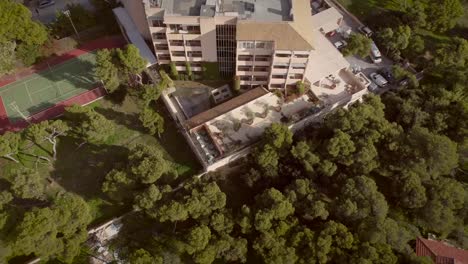 Vista-aérea-de-un-edificio-residencial,-rodeado-de-árboles-en-Grecia.