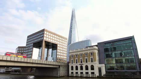 Autobuses-rojos-de-dos-pisos-pasando-por-el-puente-de-la-moderna-ciudad-de-Londres-Gran-Bretaña