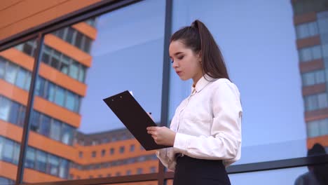 Geschäft-Mädchen-macht-Notizen-in-Arbeitspapiere-stehen-in-der-Nähe-von-Business-Center.-4K