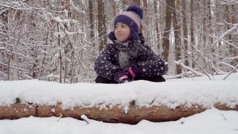 Mädchen-sitzen-hinter-einem-umgestürzten-Baum-im-Wald-4K