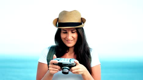 Portrait-of-beautiful-smiling-young-female-traveler-in-hat-taking-photo-using-retro-camera