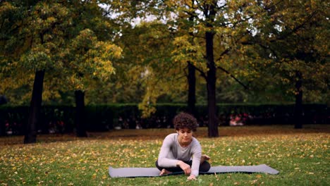 Flexible-joven-está-sentado-en-la-estera-en-pose-de-yoga-disfruta-de-relajación,-paz-y-aire-puro.-Estilo-de-vida-saludable-para-la-gente-urbana,-juventud-activa-y-concepto-de-la-naturaleza.