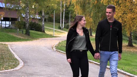 Chico-joven-con-una-chica-caminando-en-el-parque,-cogidos-de-la-mano