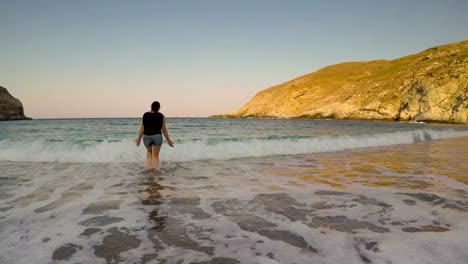 Woman-enjoying-her-summer-vacation-at-Zorkos-beach-in-Andros-playing-with-the-waves.