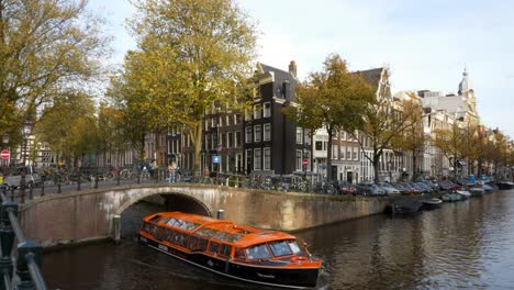 orange-tour-boat-passing-under-a-canal-bridge-in-amsterdam