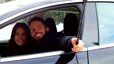 Pareja-tomando-un-selfie-en-el-coche-en-un-día-de-nieve