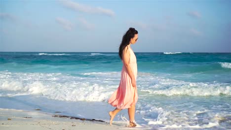 Young-beautiful-woman-in-dress-on-the-seashore-on-sunset