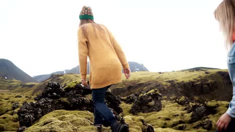 Freedom:-two-tourists-woman-raises-hands-on-the-lava-field-covered-moss-in-Iceland.-Friends-feeling-happy-after-hiking