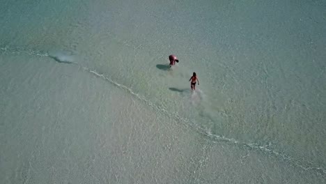 v03806-vista-aérea-de-drone-volador-de-playa-en-isla-paraíso-soleado-con-cielo-azul-aqua-mar-agua-océano-4k-2-personas-pareja-hombre-mujer-tocando-juntos-diversión-bola-blanco-Maldivas