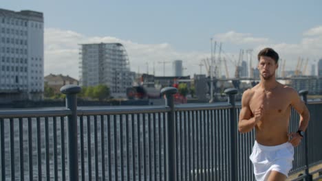 A-Very-fit-young-man-running-shirtless-though-London,-England's-Docklands.