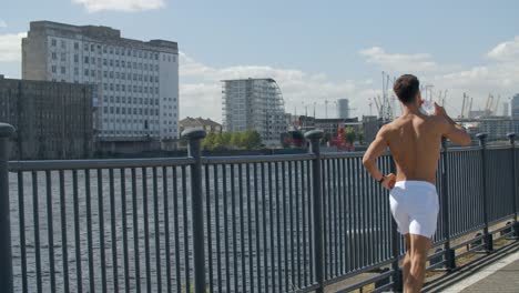 Ajuste-de-un-muy-joven-corriendo-sin-camisa-aunque-Docklands-de-Londres,-Inglaterra.