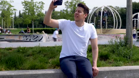 Arc-Around-a-Man-Sitting-in-a-Park-Filming-With-a-Smartphone