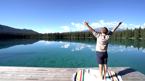 Man-arms-outreached-by-alpine-lake-in-the-Canadians-rockies