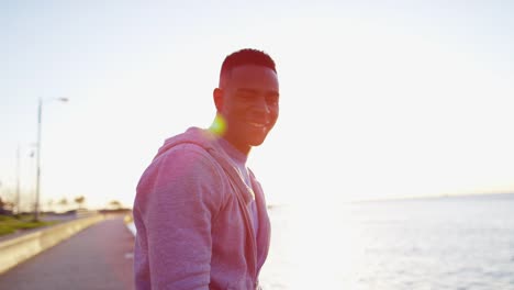 Ethnic-male-in-sun-flare-stretching-after-workout