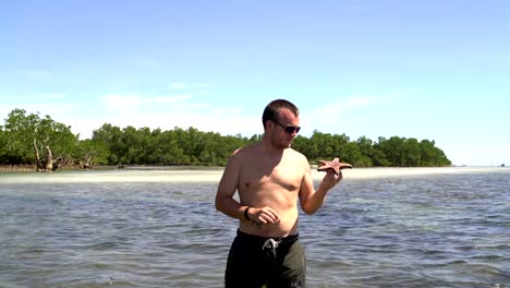 A-man-watching-a-starfish-standing-in-the-sea