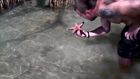 The-man-lifts-the-starfish-from-the-bottom