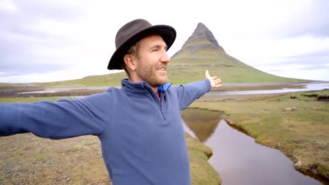 4K---Young-man-in-Iceland-arms-outstretched-for-freedom-Springtime-overcast-sky-at-famous-Kirkjufell-mountain