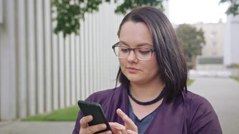 Junge-Dame-tragen-Brille-mittels-Telefon-in-der-Stadt