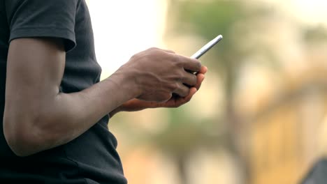 black-man's-hands-typing-on-smartphone-in-the-city.