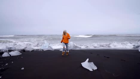 Junge-Frau-touristischen-weiblich-zu-Fuß-am-schwarzen-Sandstrand-am-Jökulsárlón-Diamond-beach