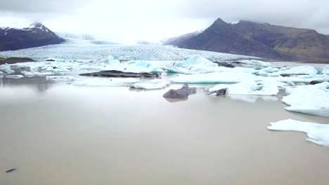 Incredible-DRONE-view-of-females-standing-by-glacier-lagoon-in-Iceland-arms-outstretched
