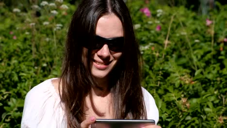 Woman-is-playing-a-game-on-mobile-phone-sitting-in-park-in-sunny-day.