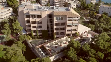 Vista-aérea-de-un-edificio-residencial,-rodeado-de-árboles-en-Grecia.