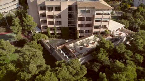 Vista-aérea-de-un-edificio-residencial,-rodeado-de-árboles-en-Grecia.