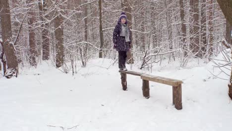 Girl-on-a-wooden-bench-in-the-winter-forest-4K