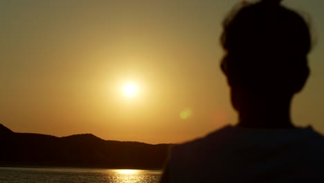 Silhouette-Of-Woman-Watching-Golden-Sunset-At-Beach