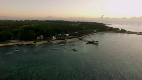 Vista-aérea-de-agua-azul-de-océano-con-olas,-corales-y-plantas-de-agua,-cámara,-hacia-la-costa,-Isla-Mauricio