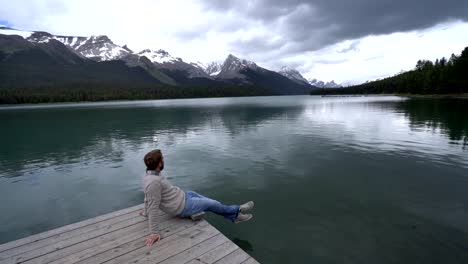 Young-man-on-lake-pier-looking-at-mountain-scenery-in-Canada