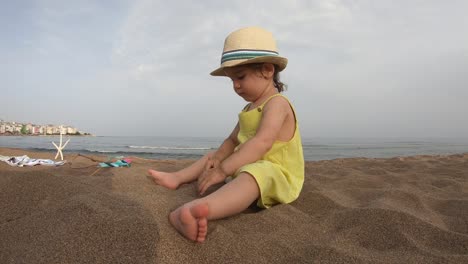 Niedliche-Mädchen-spielen-mit-Sand-am-tropischen-Strand