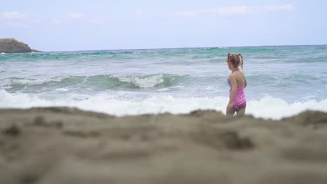 kleine-Mädchen-gehen-Sie-den-Strand-in-den-Wellen-an-einem-schönen-Tag