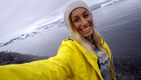 4K-Young-woman-taking-selfie-with-glacier-lake,-icebergs-floating-on-water