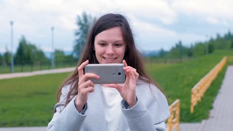 Young-woman-shoots-a-video-on-a-mobile-phone-on-the-Playground.