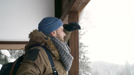 Man-Looking-at-Winter-Forest-from-Shelter