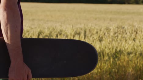 Adult-walking-next-to-Beautiful-wheat-field-holding-skateboard-with-blue-sky-and-epic-sun-light---shot-on-RED