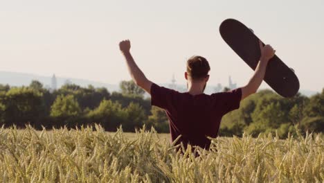 Erwachsene-stehen-bei-der-Beschaffung-von-Beautiful-Weizen-Feld-skateboard-mit-Stadt-im-Hintergrund---Schuss-auf-rot