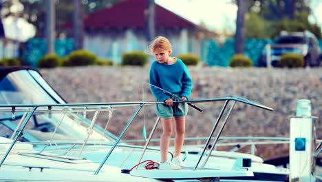 Mädchen-auf-einer-Yacht-oder-ein-Boot-besitzt-eine-Angelrute-und-befasst-sich-mit-einem-Fisch-Ort