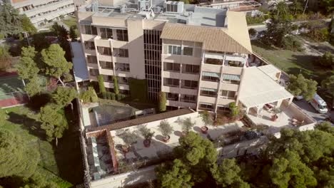 Vista-aérea-de-un-edificio-residencial,-rodeado-de-árboles-en-Grecia.