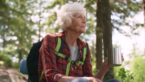 Senior-mujer-caminante-tomando-té-en-el-bosque