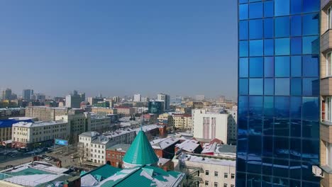 Copter-takes-off-next-to-a-skyscraper,-winter-day.-Bird's-eye-view-of-the-city